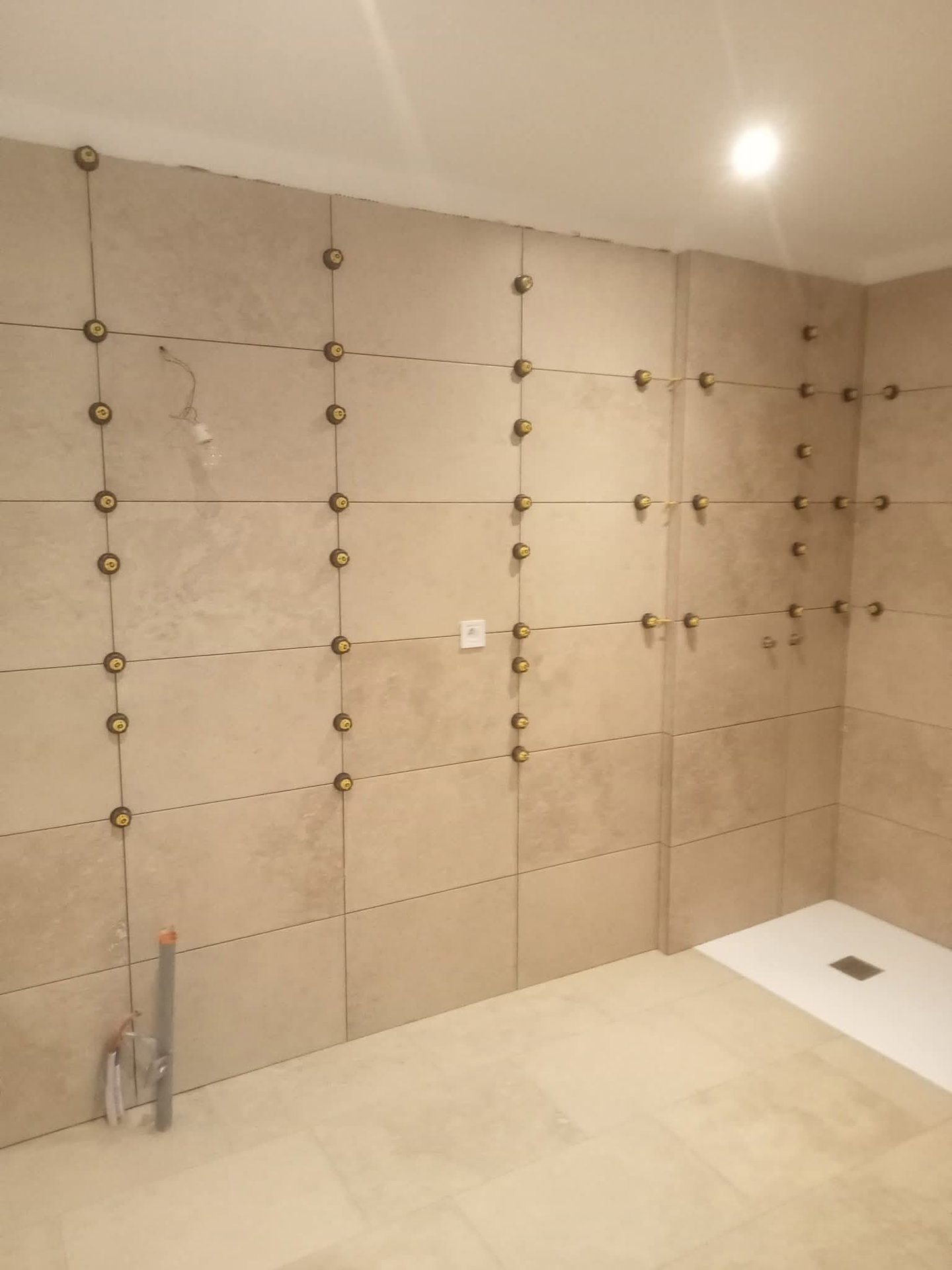 Pose de carrelage grand format sur murs et sol de salle de bain avec douche à l'italienne