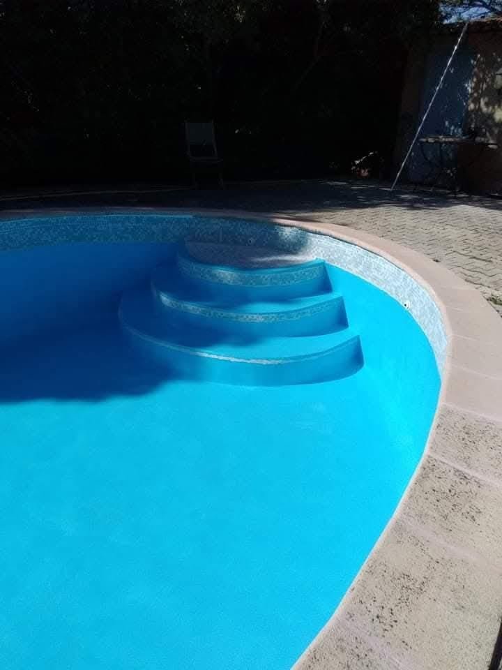 Piscine entièrement rénovée remplie d'eau bleue, revêtement neuf et escalier – après sablage
