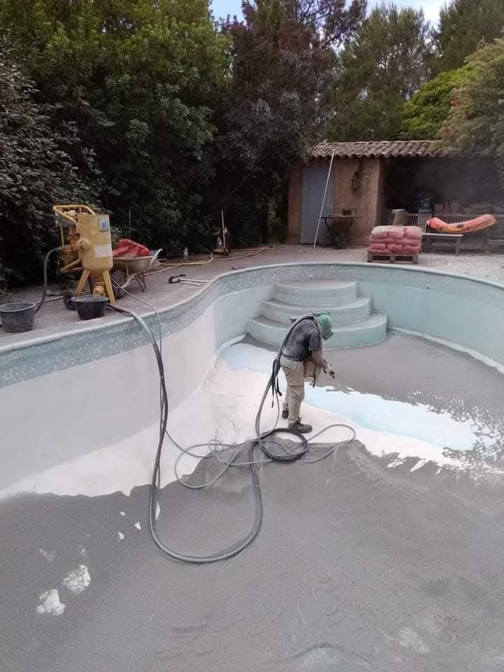 Ouvrier avec équipement de sablage décapant le revêtement intérieur d'une piscine vide – pendant les travaux