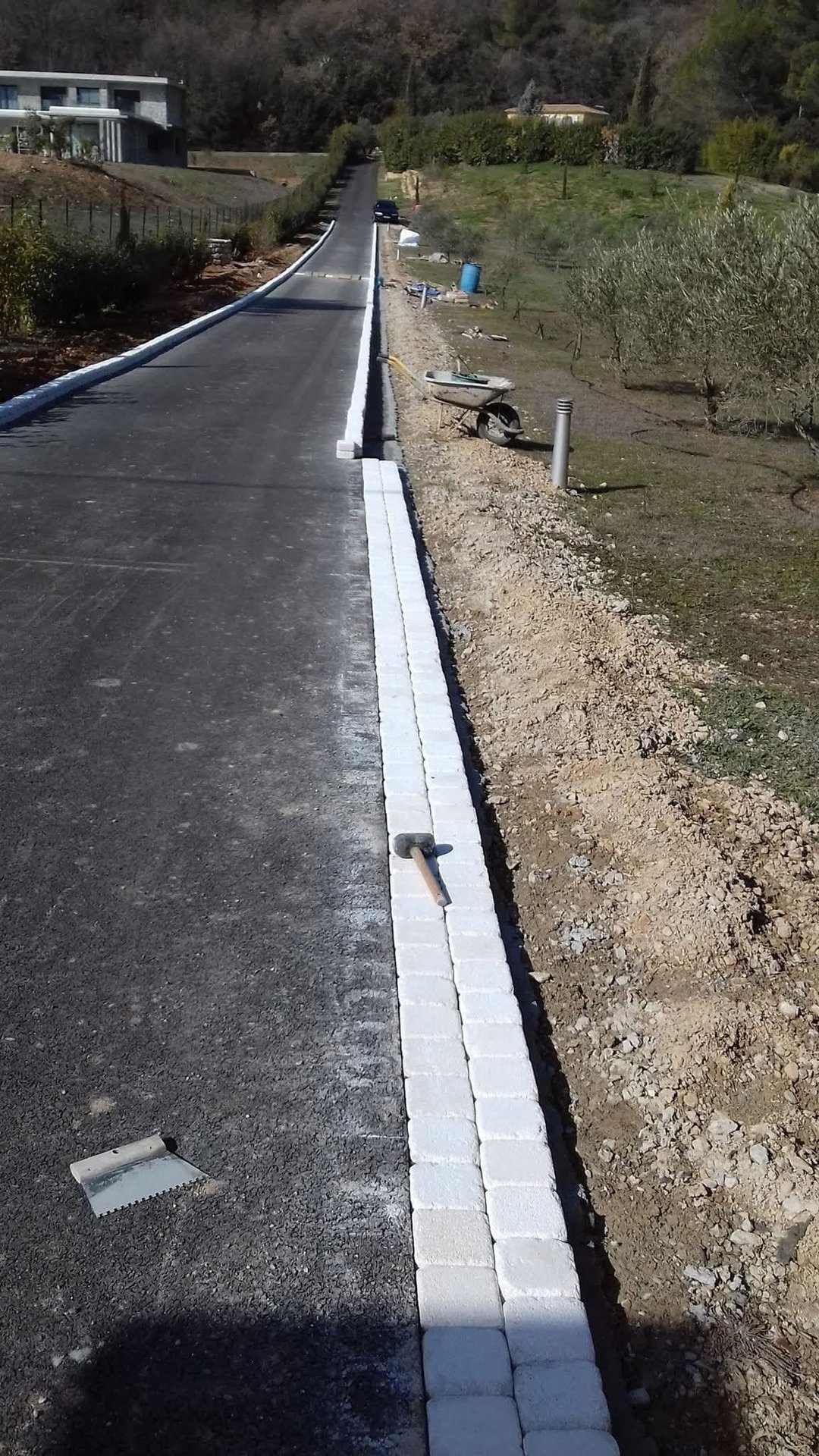 Pose des bordures blanches et revêtement béton de l'allée en cours de réalisation – pendant les travaux